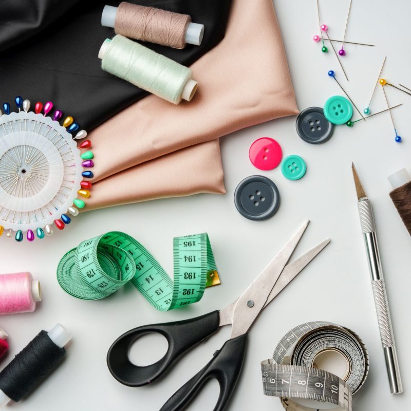 Crafting essentials for sewing projects displayed on a table with fabric, threads, and tools close up