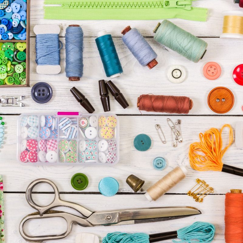 Tools and accessories for sewing on light wooden background. Tools and accessories for sewing on light wooden background. Top view. Flat lay composition.